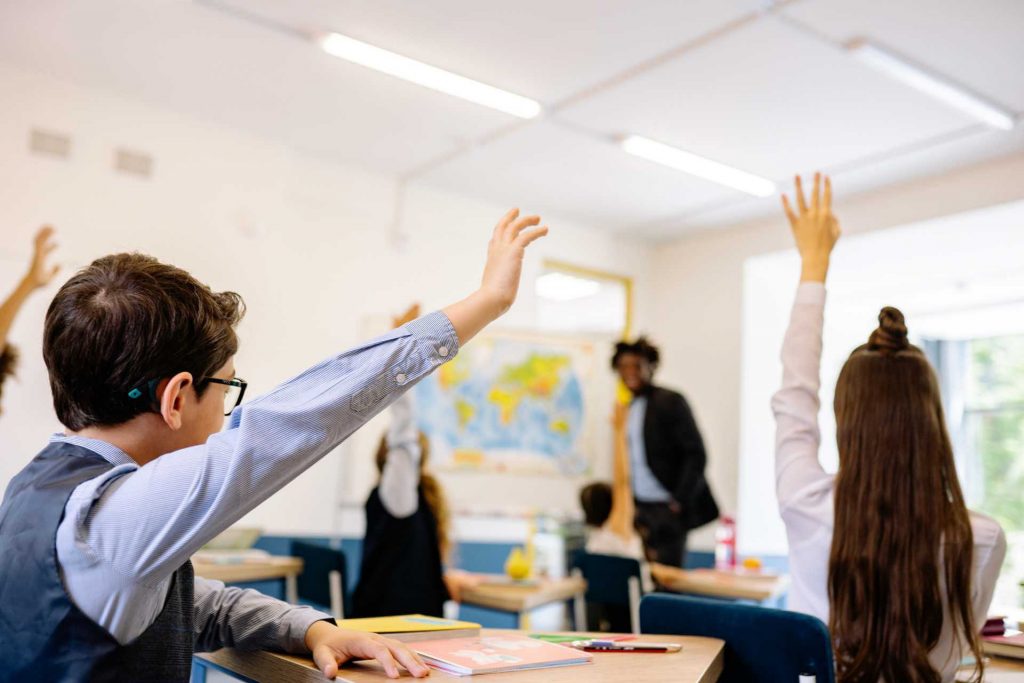 Children raising hands at the classroom