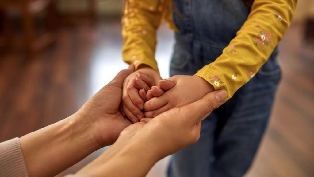 Parent holds child's hands to support her
