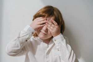 autistic child closing his eyes - symptoms of autism