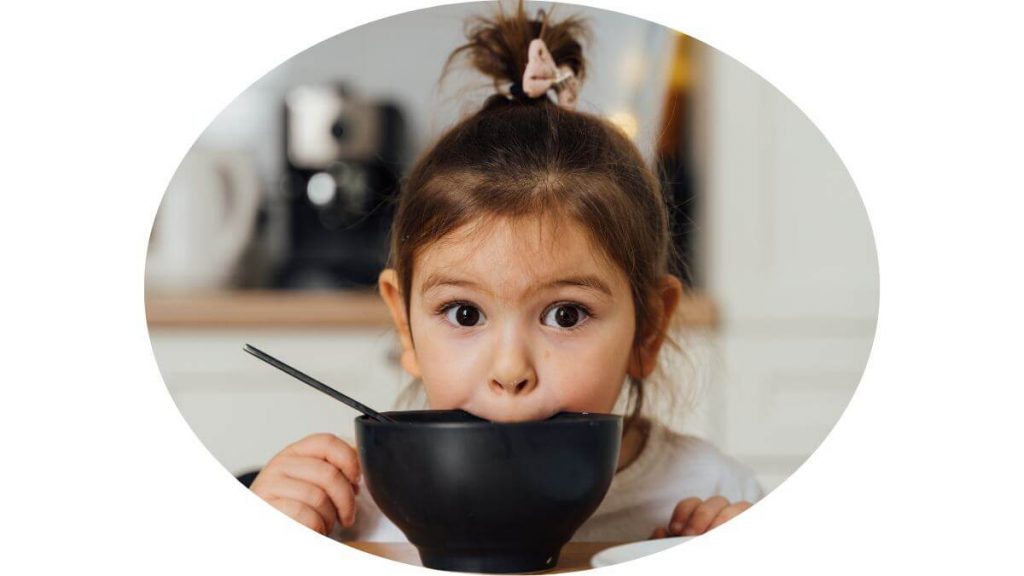 an image of agirl biting soup bowl